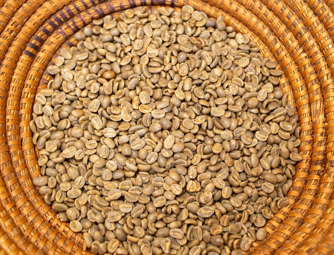 Dried green coffee beans in a woven basket