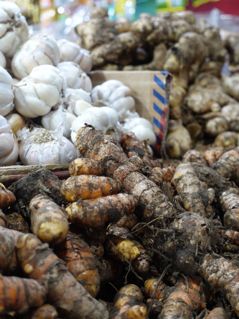 Garlic and rhizome spices piled at a traditional market